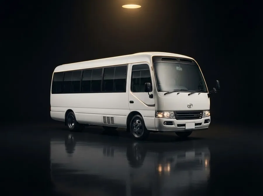 White Toyota Coaster minibus in a dark studio